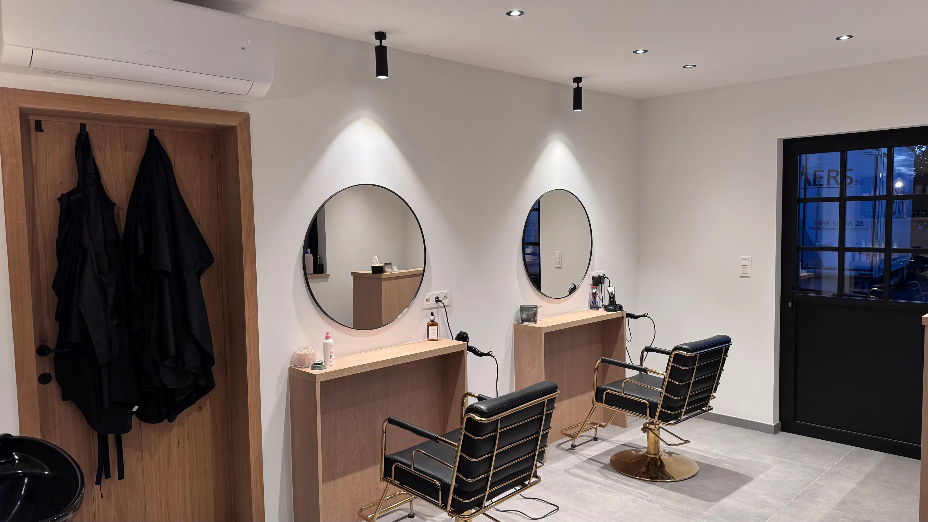 Interieur van kapsalon Snip’Em in Herenthout, met kappersstoelen en spiegels.